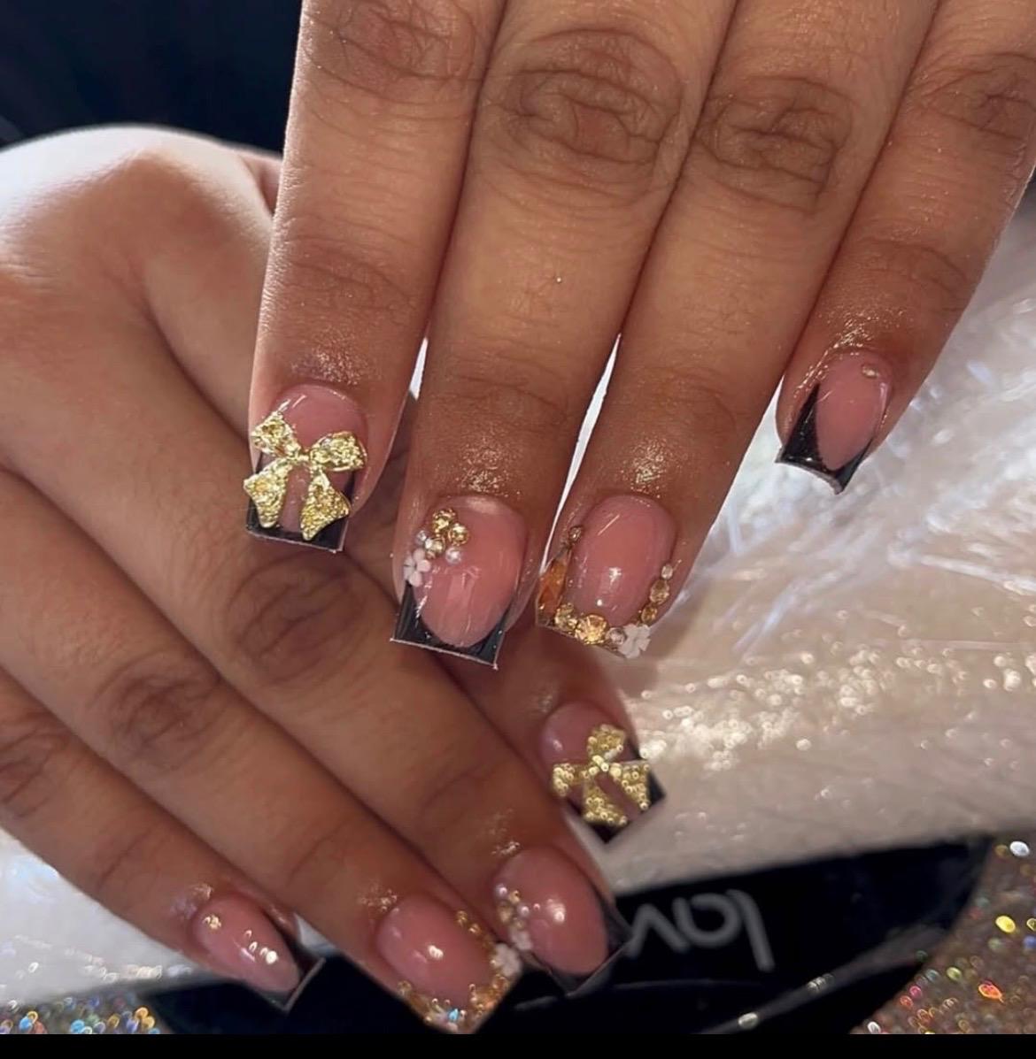 Glossy black French with gold bows and rhinestones.