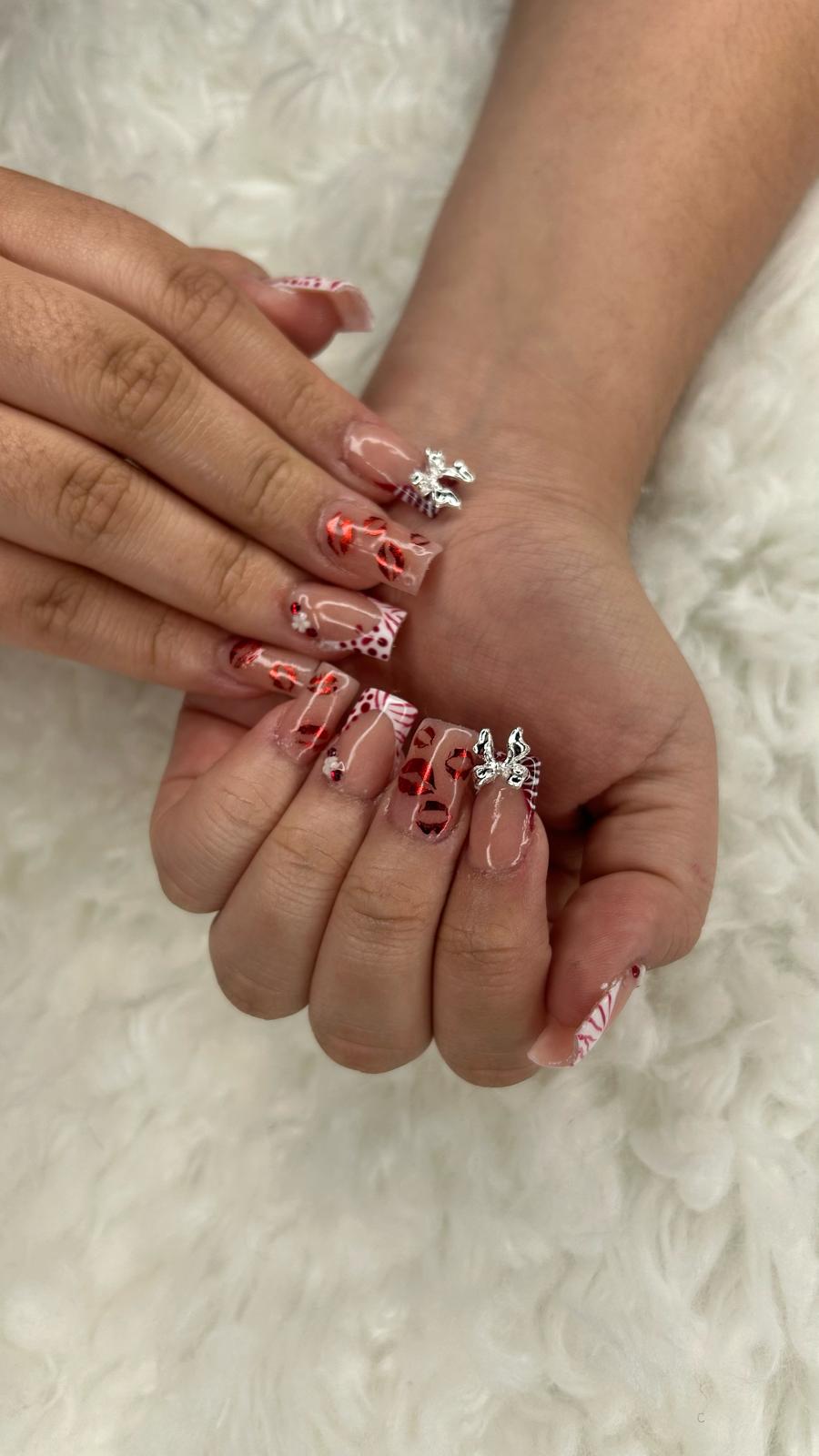 Metallic red nail art with silver bow charms.