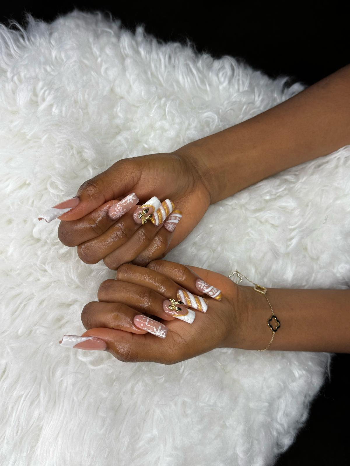 Nude coffin nails with white swirls and gold charms.